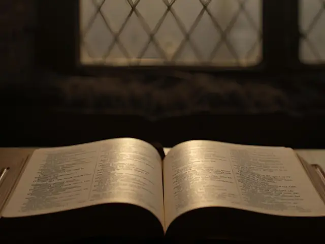 Open Bible on a wooden surface with gentle light from a window behind it, used as the featured image for a Proverbs 3:5–6 blog post.