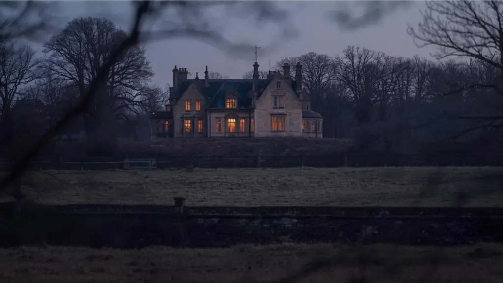 Old English manor house at dusk with warm lights in a few windows, used as the featured image for a blog post reviewing Julie Klassen’s The Secret of Pembrooke Park.