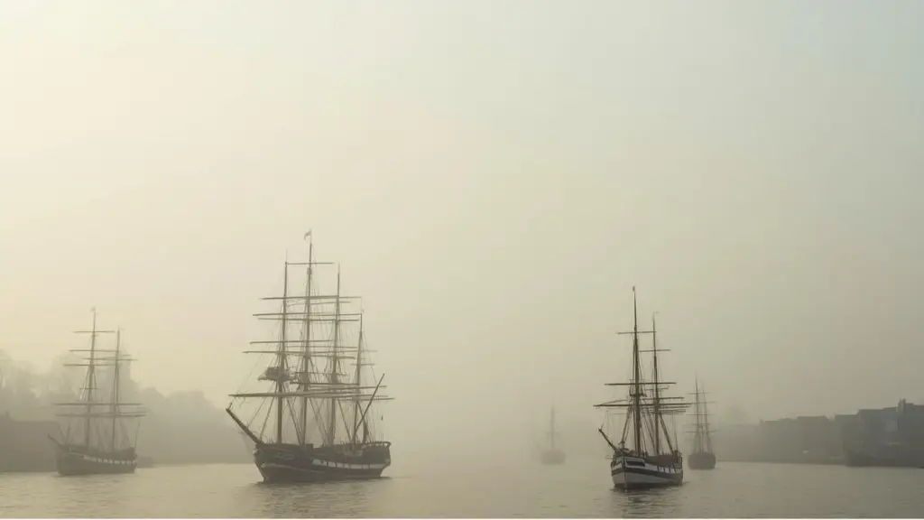 Misty view of an old harbor with sailing ships and distant buildings at dawn, used as the featured image for a blog post reviewing Roseanna M. White’s Ring of Secrets.